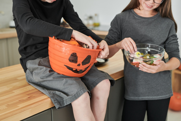 Brother and Sister Hold Bowls of Halloween Treats